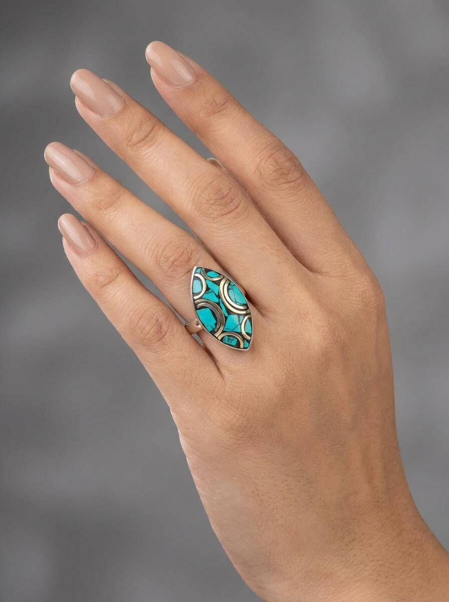 Hand wearing a turquoise ring with a gray background