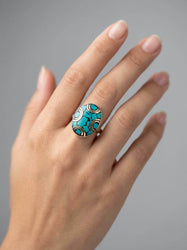 Turquoise ring on a hand against a gray background