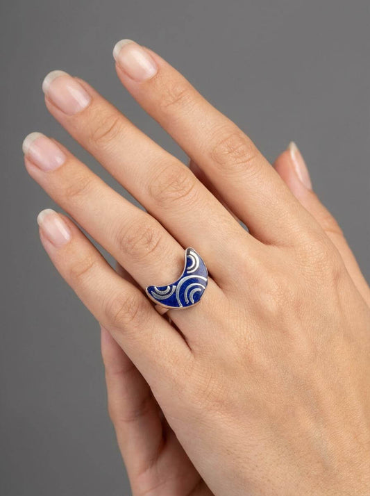 Hand wearing a blue and white patterned ring on a gray background